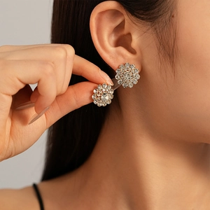 Elegant gold flower stud earrings with sparkling crystals worn by a female model