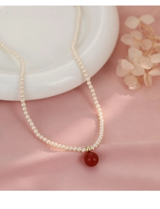 Vue rapprochée d'un collier de perles vintage français avec pendentif perle rouge sur soie