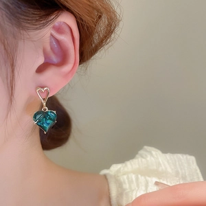 Detailed view of heart-shaped gold-plated earrings with emerald green zircon crystals