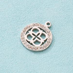 Macro shot of silver clover pendant with sparkling rhinestones on blue background