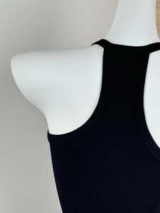 Close-up of black ribbed knit vest showing V-neckline and shoulder strap details