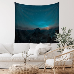 Detail of galaxy mountain tapestry hanging above a minimalist sofa in a modern room