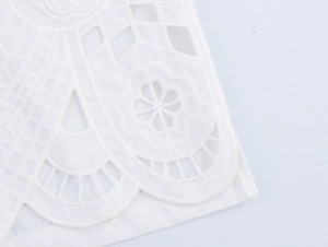 Gros plan détaillé d'une broderie florale ajourée blanche sur un tissu en coton