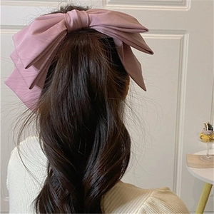 Close-up of a large pink floral chiffon hair clip worn on a ponytail for a fairy look
