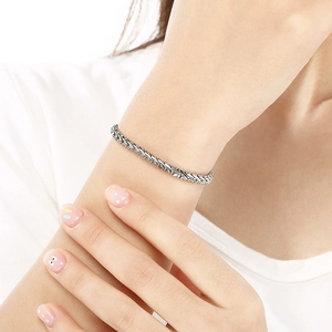 Détail d'un bracelet en chaîne argentée à texture tressée porté au poignet d'une femme