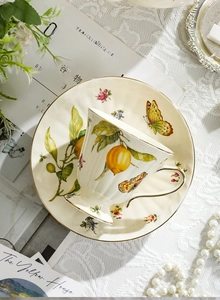 Detail of vintage ceramic cup set with lemon patterns and gold rim on lace cloth