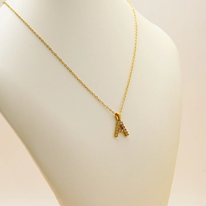 Detailed close-up of golden letter A pendant with sparkling cubic zirconia on model