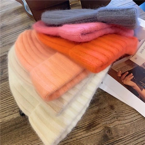 Detailed pile of colorful mohair knit beanies on a wooden table with magazines