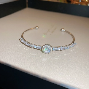 Detail of silver open bangle with a central round zircon and pavé diamond setting