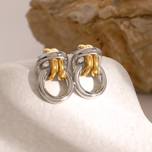 Elegant two-tone gold and silver knotted hoop earrings displayed on white textured stone