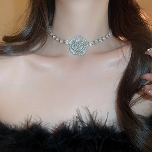 Close-up of a silver flower necklace featuring sparkling rhinestones on a female neck