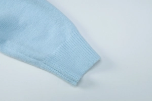 Detail of light blue knit sweater showing ribbed cuff texture and fine stitching work