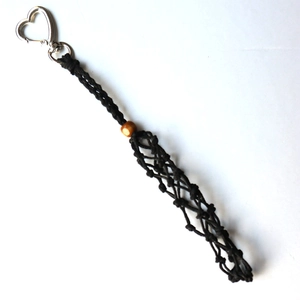 Detail of handmade woven net bag pendant with heart-shaped metal clasp and brown wood bead