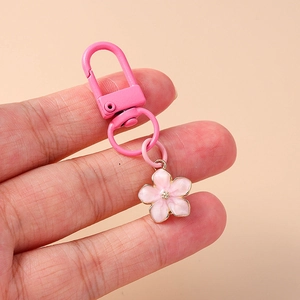 Detail of pink enamel cherry blossom keychain with gold accents and lobster clasp