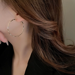 Close-up of elegant gold hoop earrings worn by a model with a minimalist metal design