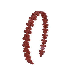 Detail of red-brown acrylic floral headband showing matte texture and inner non-slip teeth
