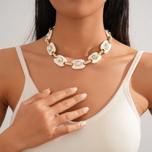 Gros plan du collier à maillons ovales dorés avec émail blanc et cristaux brillants