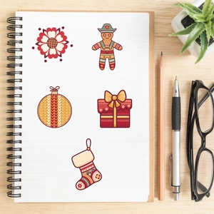 Close-up of five cartoon Christmas stickers on a spiral notebook with festive folk patterns