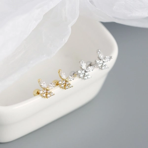 Detailed shot of sparkling butterfly stud earrings in gold and silver finish with gems