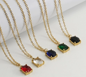 Detail of 18K gold necklaces featuring square-cut gems in red, blue, green, white, and black