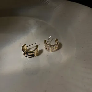 Boucles d'oreilles asymétriques en C plaquées or avec émail noir et pierres zircon