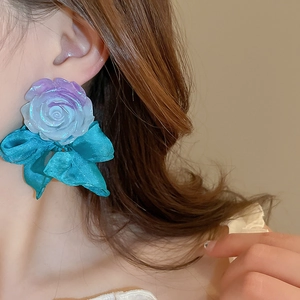 Close-up of elegant purple resin flower earrings with blue silk bow on a model