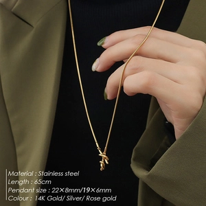 Long stainless steel snake chain necklace with gold knot pendant shown on model