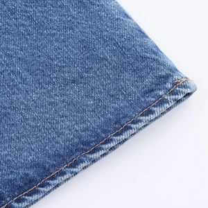Detail of blue denim dress featuring orange contrast stitching and twill cotton texture