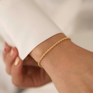 Minimalist 18K gold-plated stainless steel rope chain bracelet worn on a woman's wrist
