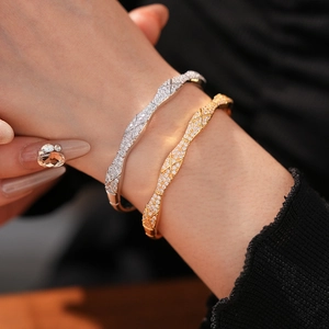 Detail of gold and silver criss-cross bangles with pavé zircon settings on wrist