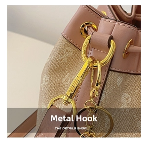 Detail view of the shiny gold alloy swivel hook and bear pattern canvas on a crossbody bag