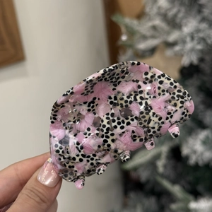 Close-up of semi-circle acetate hair claw clip with black dots and pink texture patterns