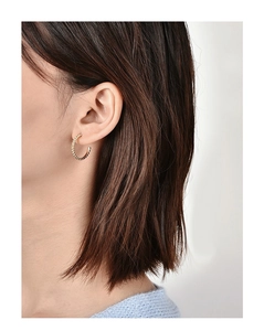 Close-up of gold plated spiral bead texture hoop earrings worn on a model's ear