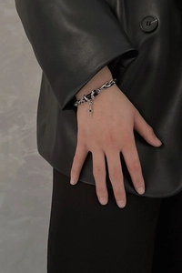 Detail of silver titanium steel cross bracelet worn with a black leather jacket cuff