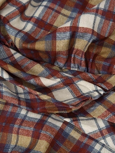 Macro detail of the red and navy plaid fabric texture on a casual mini dress