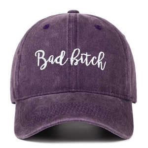 Detailed close-up of cursive white embroidery on a washed purple cotton baseball cap