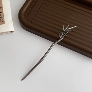 Detailed view of a metal bamboo-shaped hair pin with leaf accents in dark gunmetal finish