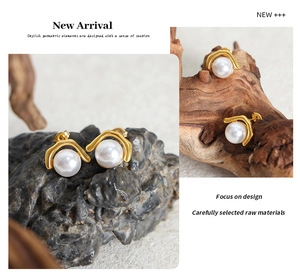 Detail of gold-plated geometric earrings with imitation pearls on natural stone and wood