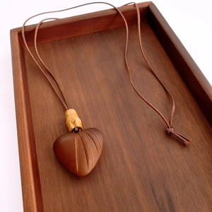 Gros plan d'un pendentif en bois en forme de cœur avec nervures sculptées et cordon