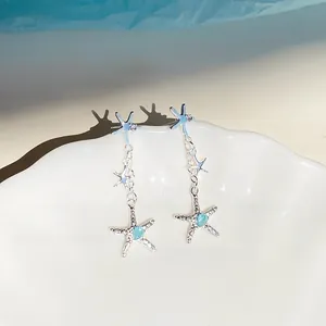 Vue détaillée des boucles d'oreilles pendantes étoile de mer avec cristal bleu cœur