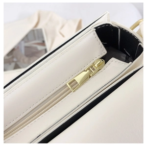 Detailed macro view of gold-tone metal zipper and precise stitching on white leather bag