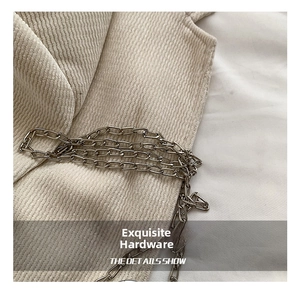 Close-up of shiny silver metal chain on beige corduroy fabric texture detail