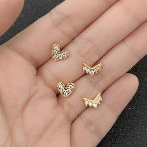 Golden 18k plated heart and V-shaped stud earrings with zircon held in palm