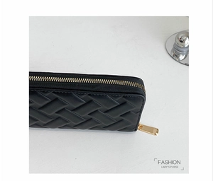 Detailed close-up of black PU leather purse with woven texture and gold metal zipper