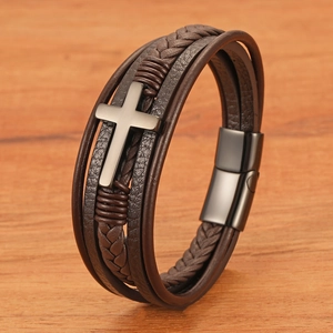 Brown multilayer braided leather bracelet with stainless steel cross charm on wood background