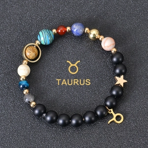 Detail of Taurus zodiac bracelet with black matte beads and celestial gold pendants