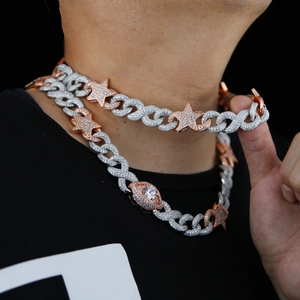 Close-up of hip hop cuban chain necklace with star and eye pendants in silver and rose gold