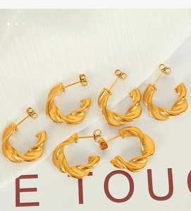 Detailed view of gold twisted C-shape hoop earrings with a textured spiral design