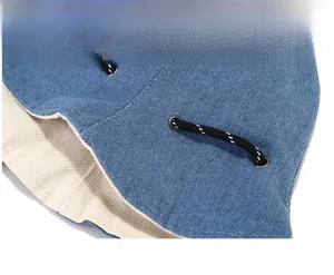 Macro shot of blue denim bucket hat detail with woven drawstring and silver eyelet