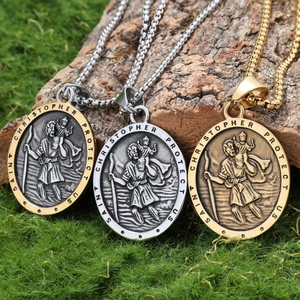 Three Saint Christopher necklaces in gold and silver on a moss-covered wooden stump
